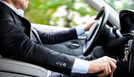Interior shot of man in a suit driving a car. Europeo Cars offer low prices to rent a car in Crete.